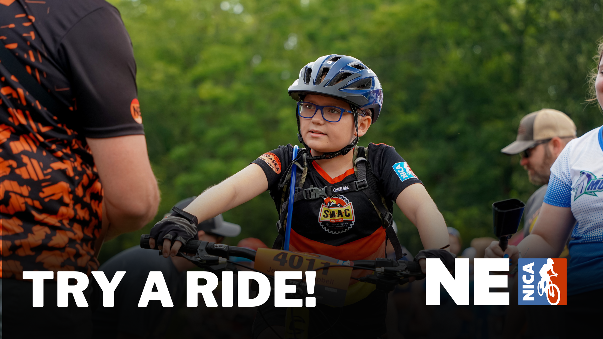 A young cyclist wearing glasses and a helmet listens attentively to an adult before a bike ride; text reads TRY A RIDE! with NICA NE logos, and the background is green and outdoors.